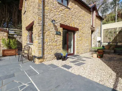 a stone house with a patio and a building at Blue Bell Cottage in St Austell