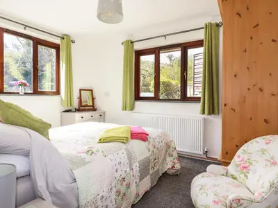 a bedroom with two beds and two chairs at Rose Bud Cottage in St Austell