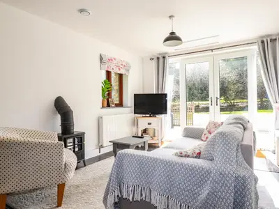 a living room with two couches and a tv at Rose Bud Cottage in St Austell