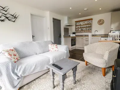 a living room with a couch and a table at Rose Bud Cottage in St Austell