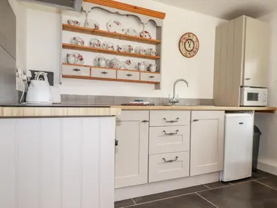 a kitchen with white cabinets and a sink at Rose Bud Cottage in St Austell