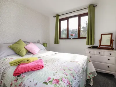 a bedroom with a bed with pink and green towels on it at Rose Bud Cottage in St Austell