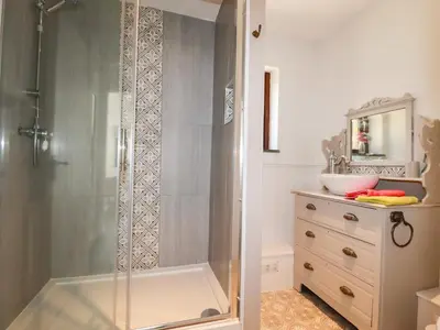 a shower with a glass door in a bathroom at Rose Bud Cottage in St Austell