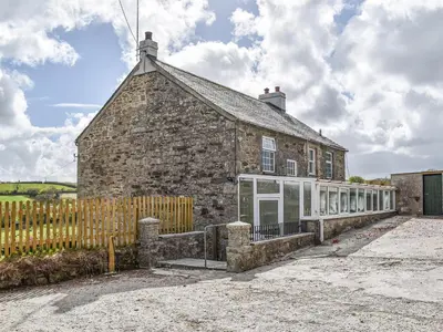 an old stone house with a wooden fence in front of it at Lower Colvannick in Cardinham