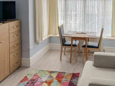 a living room with a table and chairs and a television at Summer Breeze in Newquay