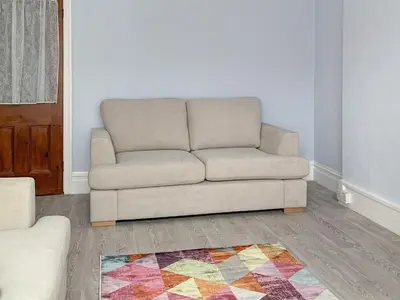 a couch sitting in a living room with a rug at Summer Breeze in Newquay