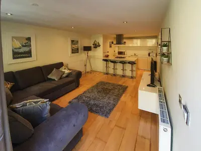 a living room with a couch and a kitchen at Apartment 4, Zinc in Newquay