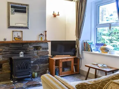 a living room with a fireplace and a television at The Old Sweetshop in Par