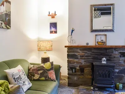 a living room with a fireplace and a green couch at The Old Sweetshop in Par