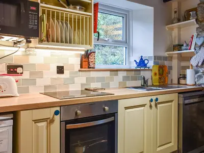 a kitchen with yellow cabinets and a stove top oven at The Old Sweetshop in Par