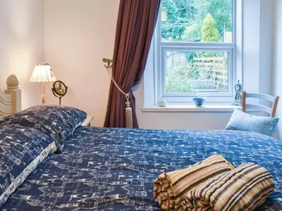 a bedroom with a blue bed with a window at The Old Sweetshop in Par