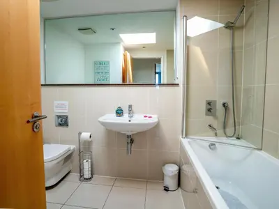 a bathroom with a sink and a tub and a mirror at Penthouse 47 Zinc in Newquay