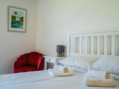 a bedroom with a white bed and a red chair at Penthouse 47 Zinc in Newquay