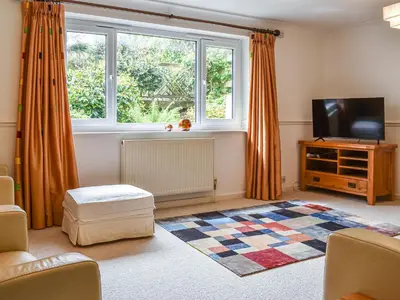 a living room with a tv and a window at Heather Cottage in Saint Erth