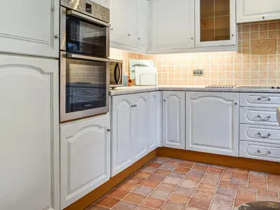 a white kitchen with white cabinets and appliances at Heather Cottage in Saint Erth