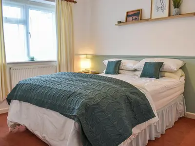 a bedroom with a large bed with a green comforter at Heather Cottage in Saint Erth