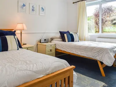two beds in a room with a window at Heather Cottage in Saint Erth