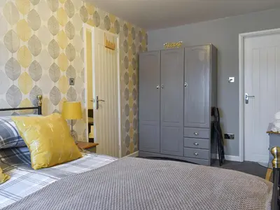 a bedroom with a bed with a yellow pillow and a cabinet at The Lily Pad in St Merryn
