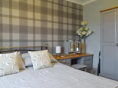 a bedroom with a bed and a desk with a television at The Lily Pad in St Merryn
