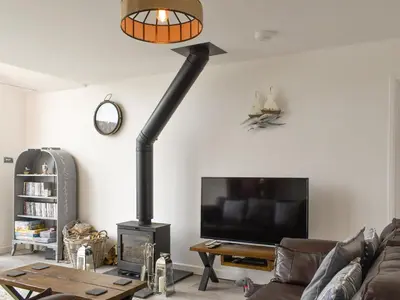 a living room with a fireplace and a tv at The Lily Pad in St Merryn