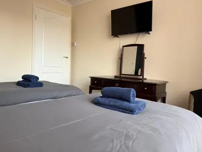 a bedroom with two beds and a dresser with a television at Apartment 11 Chester Road Newquay in Newquay