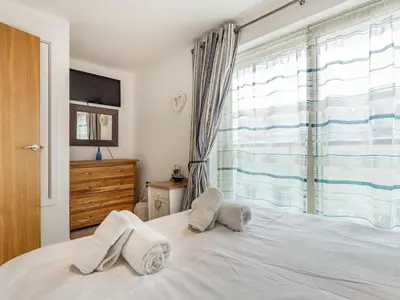 a bedroom with a white bed with towels on it at Constantine Bay Cottage in Padstow