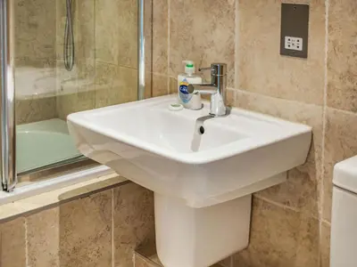 a white sink in a bathroom next to a shower at Constantine Bay Cottage in Padstow