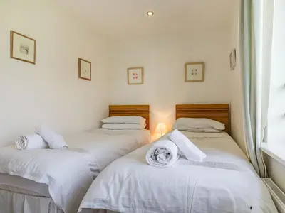 two beds in a room with white sheets and towels at Constantine Bay Cottage in Padstow