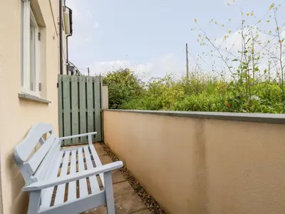 a white bench sitting on the side of a building at Constantine Bay Cottage in Padstow