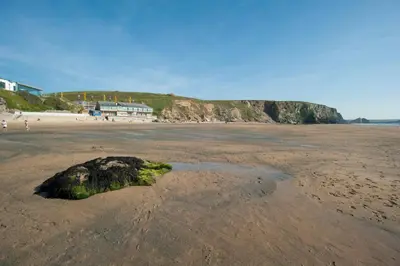 a rock in the sand on a beach at Tregurrian Villas in Newquay