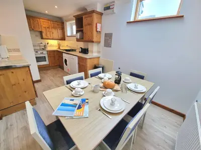 a kitchen and dining room with a wooden table and chairs at Tregurrian Villas in Newquay