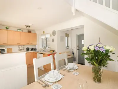 a kitchen and dining room with a table and flowers at Charleston Cottage in Falmouth