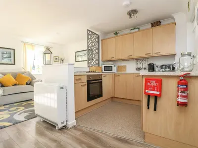 a kitchen with wooden cabinets and a white refrigerator at Charleston Cottage in Falmouth