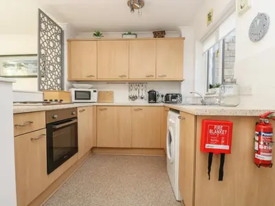 a kitchen with wooden cabinets and a dishwasher at Charleston Cottage in Falmouth