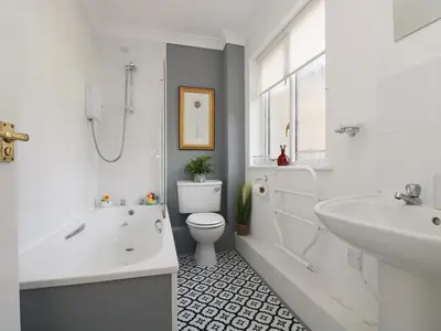 a white bathroom with a toilet and a sink at Charleston Cottage in Falmouth
