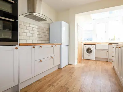 a kitchen with white cabinets and a washer and dryer at Seawynds in Newquay