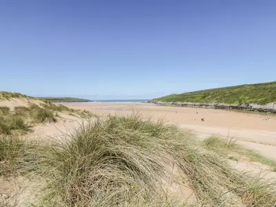 a beach with sand dunes and people on the beach at Seawynds in Newquay