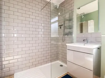 a white tiled bathroom with a sink and a shower at Seawynds in Newquay