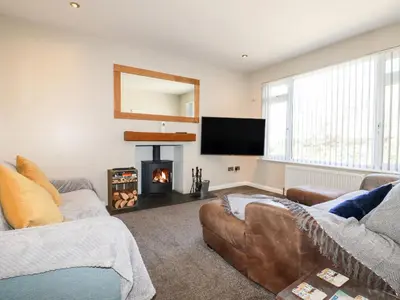 a living room with a fireplace and a flat screen tv at Seawynds in Newquay
