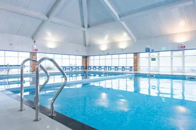 a large indoor swimming pool with blue water at St Ives Bay Beach Resort in Phillack