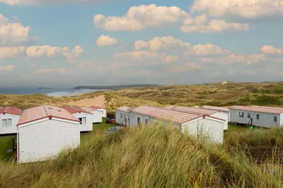 a row of beach huts in the sand on the beach at St Ives Bay Beach Resort in Phillack
