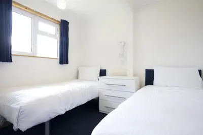 two beds in a room with two windows at St Ives Bay Beach Resort in Phillack
