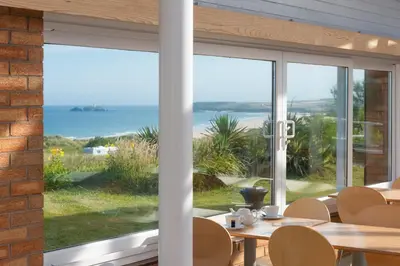 a dining room with a view of the ocean at St Ives Bay Beach Resort in Phillack