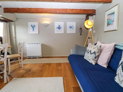 a living room with a blue couch and a table at 4 Trenhaile Terrace in Truro