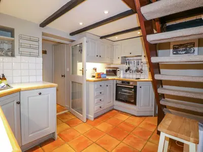 a kitchen with white cabinets and an orange tile floor at 4 Trenhaile Terrace in Truro