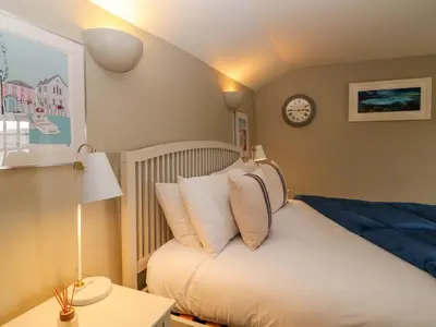 a bedroom with a bed and a clock on the wall at 4 Trenhaile Terrace in Truro