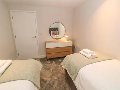 a bedroom with two beds and a mirror and a dresser at Porth Cove in Newquay