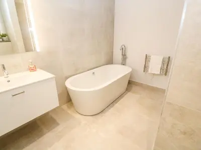 a white bathroom with a tub and a sink at Porth Cove in Newquay