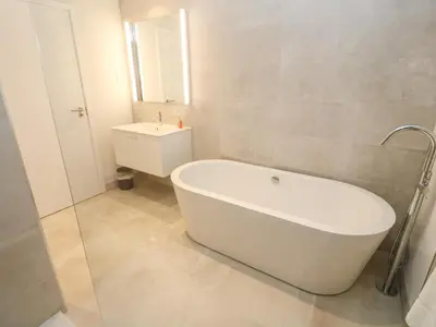 a white bathroom with a tub and a sink at Porth Cove in Newquay