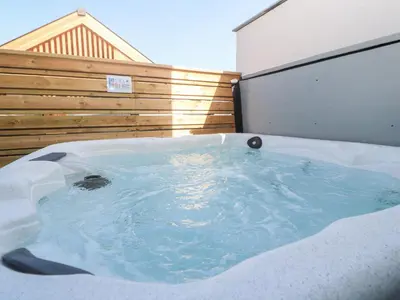 a jacuzzi tub in the backyard of a house at Porth Cove in Newquay